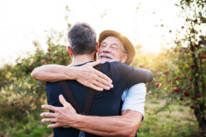 A young man and his senior father share a hug at one of the best memory care communities in San Juan Capistrano