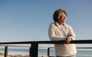 A senior woman standing on dock looking out at the ocean