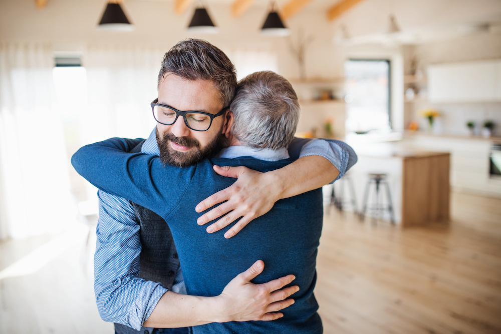 An adult man and his senior father share a hug