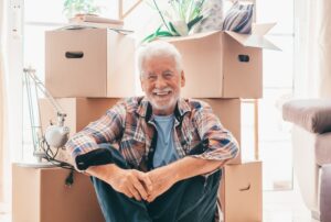 A senior man sitting in front of moving boxes before he transitions to the memory care near me