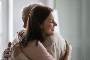 A young woman hugs her senior father during a conversation